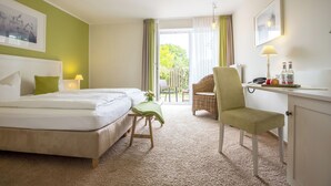 A hotel room with a bed, a desk with a lamp, a chair, and a view of the outdoors. - Paulsen's Landhotel und Restaurant (Bohmstedt)