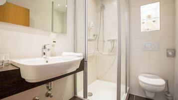 A modern bathroom with a glass-enclosed shower, a white sink, and a toilet.
