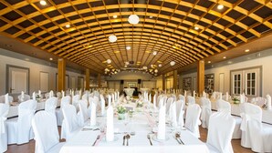 A banquet hall with round tables, white tablecloths, and chairs with white sashes. - Paulsen's Landhotel und Restaurant (Bohmstedt)