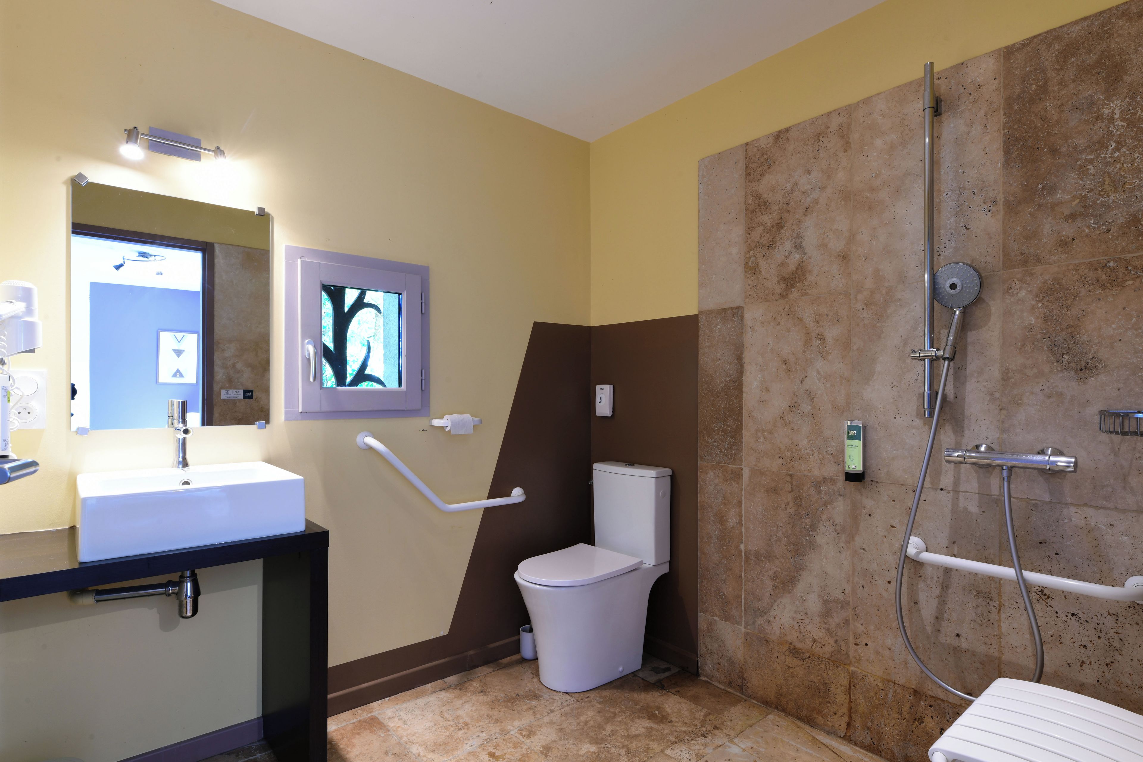 A bathroom with a white sink, a toilet, a shower with a handheld showerhead, and a towel rack.
