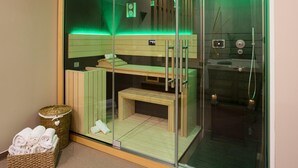 A glass-enclosed sauna with a wooden bench, a small table, and a basket of towels. - L'Auberge de Larressingle (Larressingle)