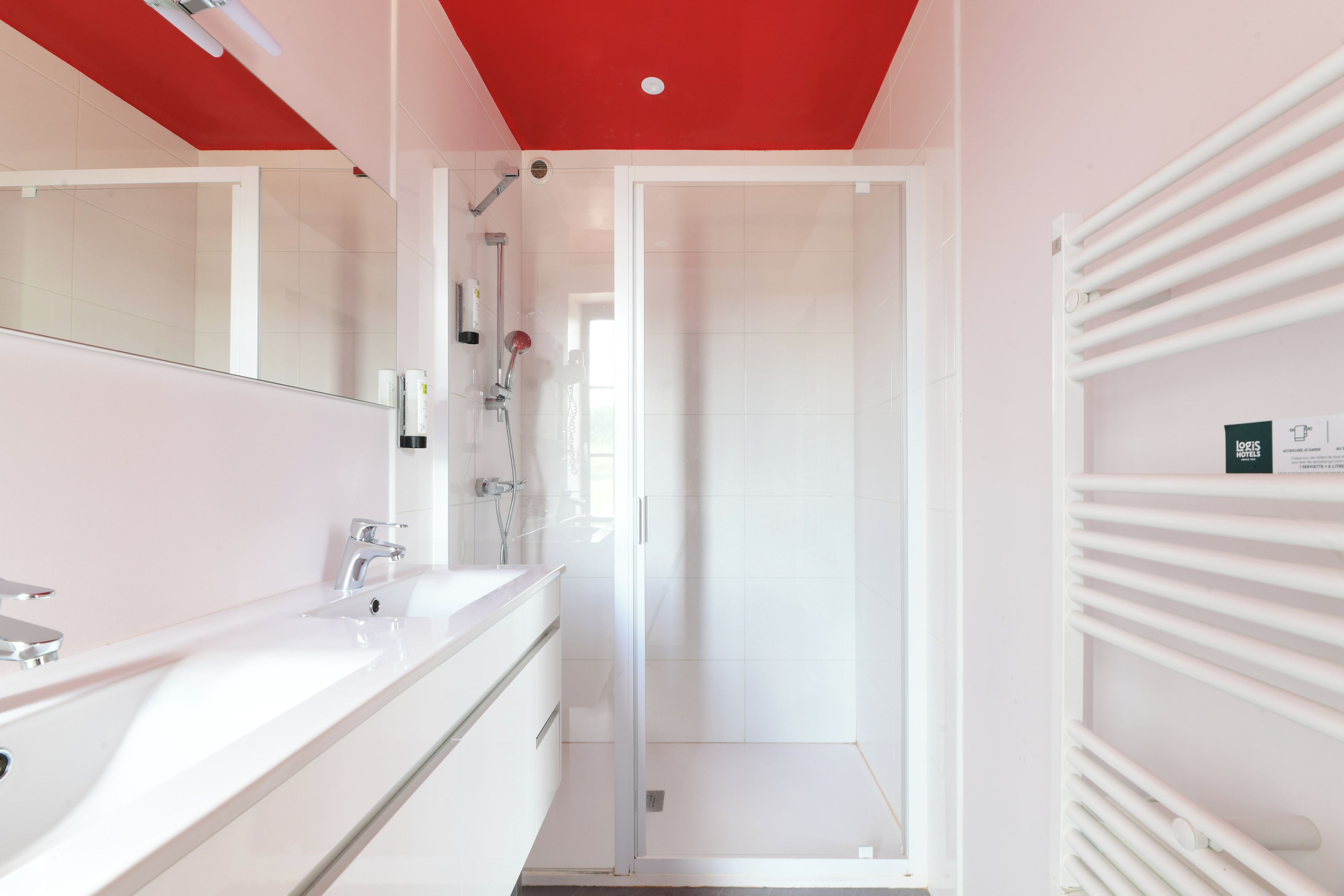 A modern bathroom with a white vanity, a shower with a glass door, and a towel rack.