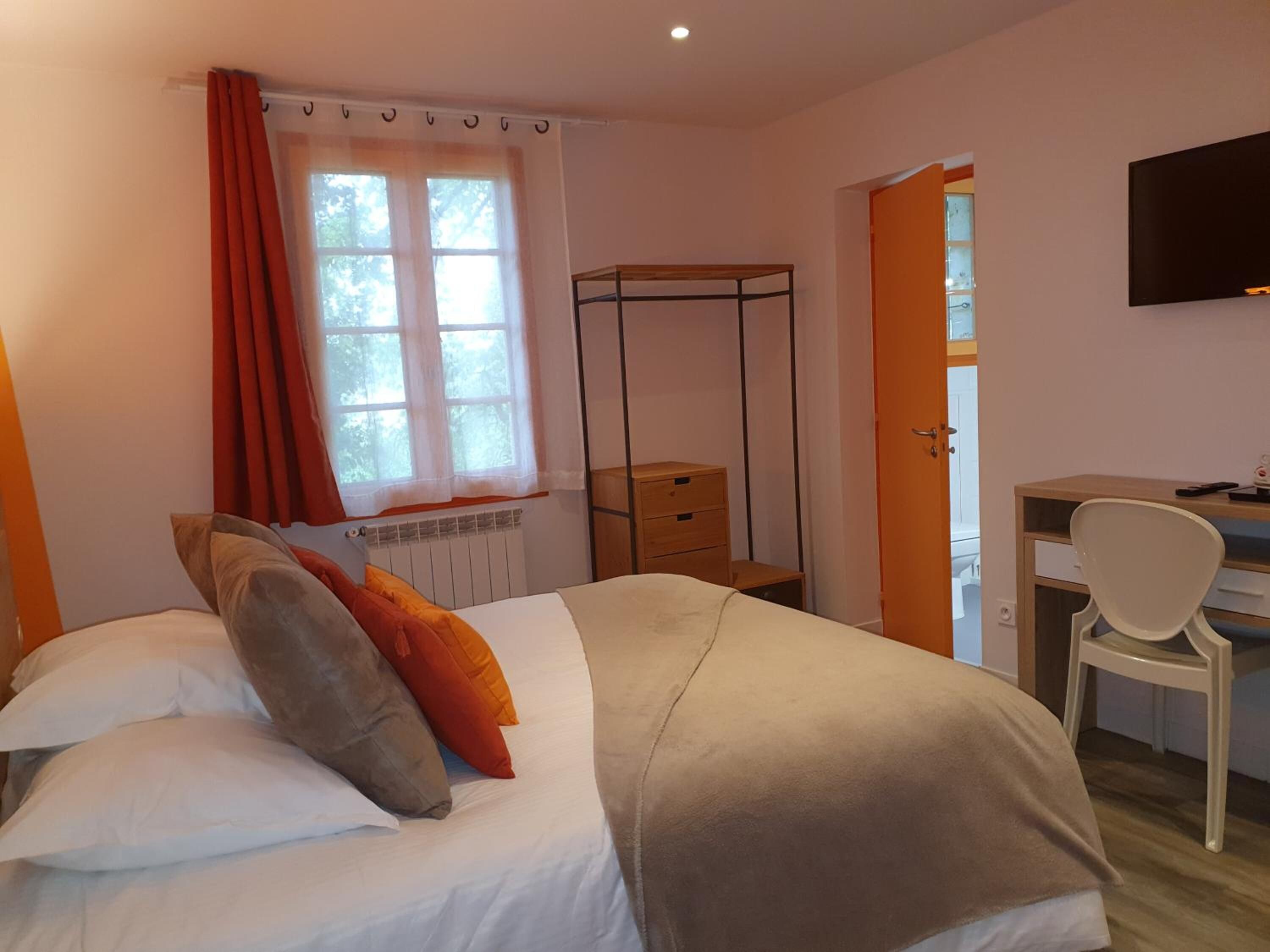 A bedroom with a bed, a desk, and a chair.