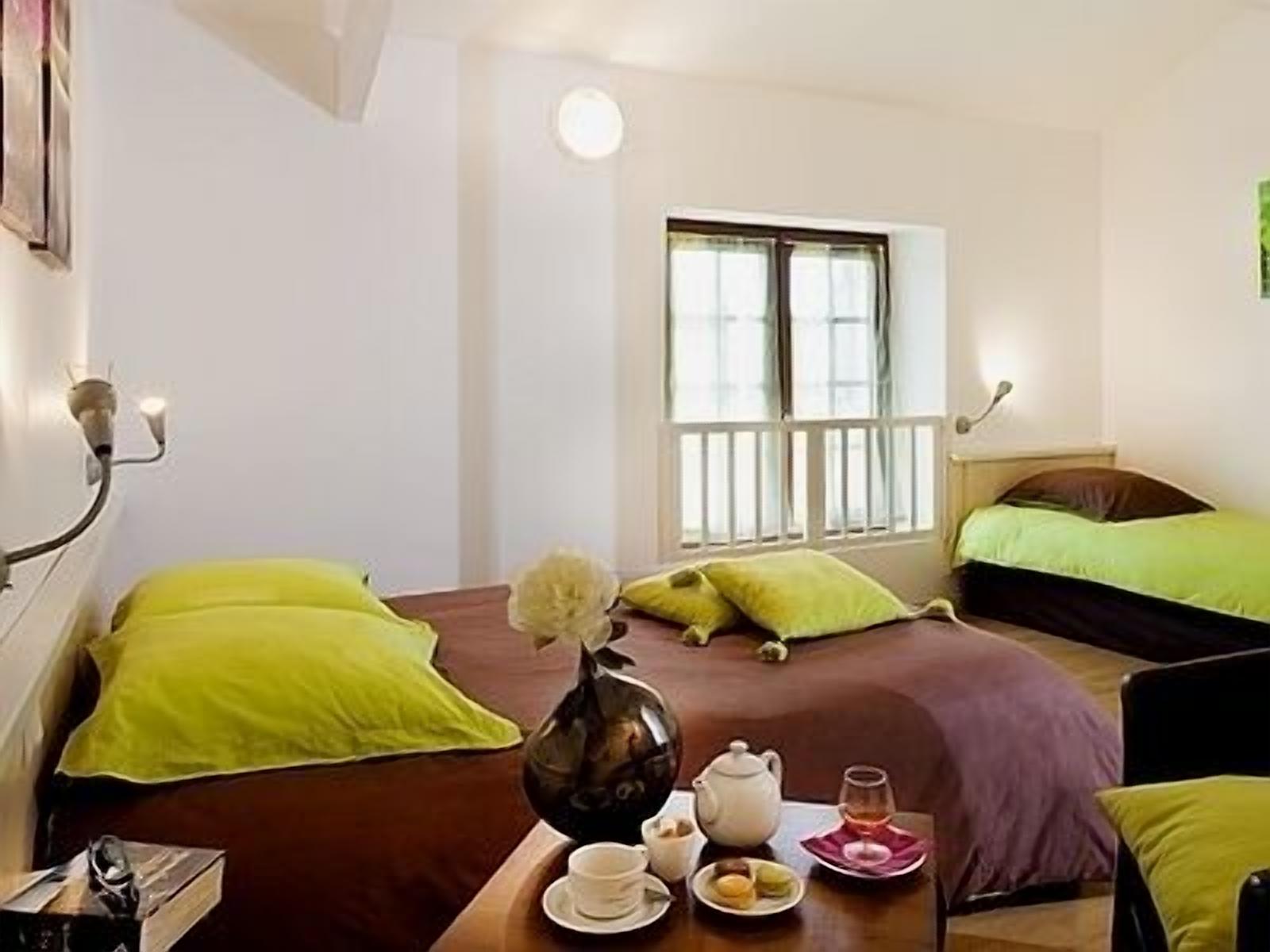 A room with two beds, a table with tea and snacks, and a window with blinds.