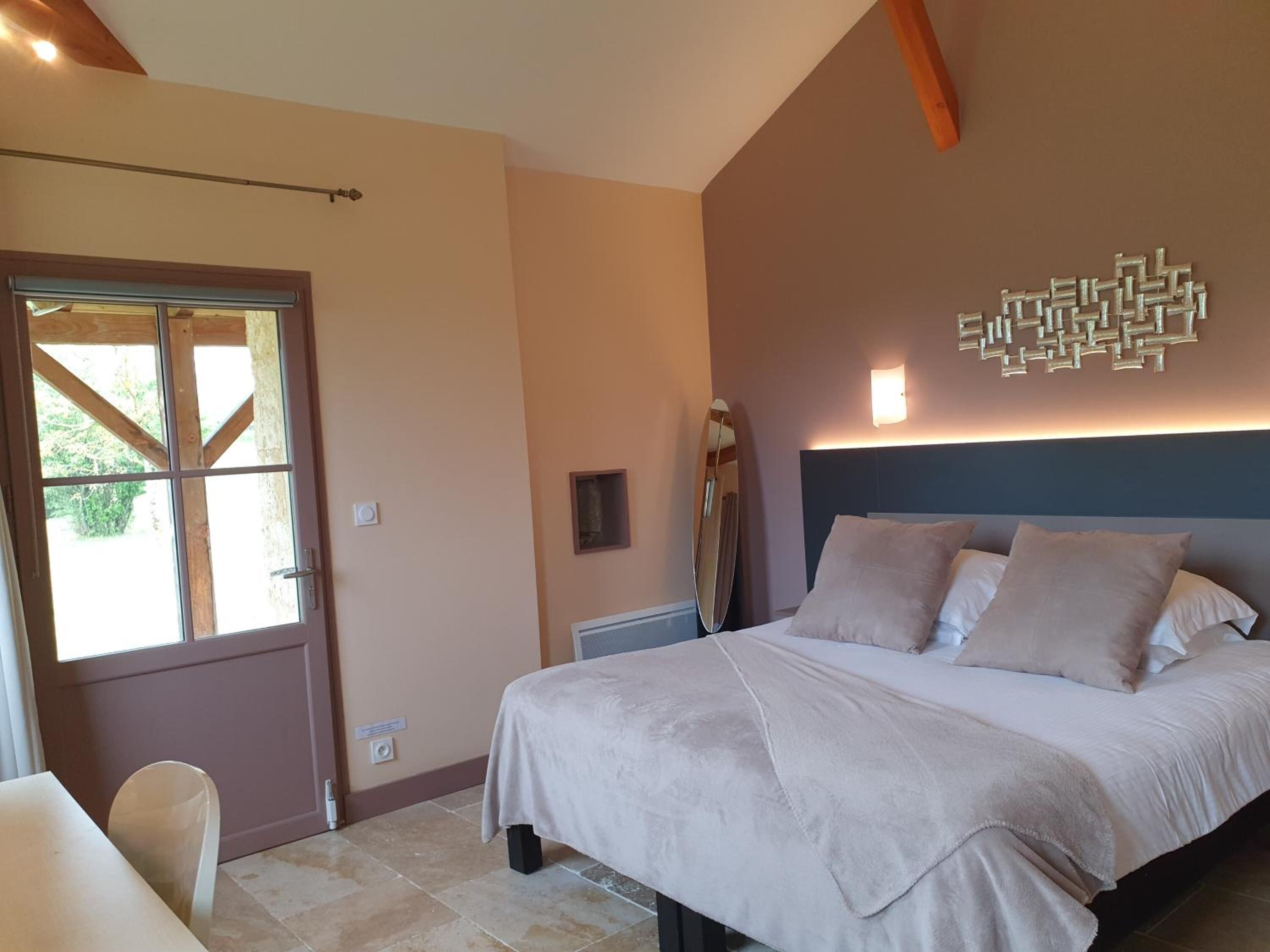 Un dormitorio con cama, una puerta con ventana, una lámpara de pared y un adorno en la pared.