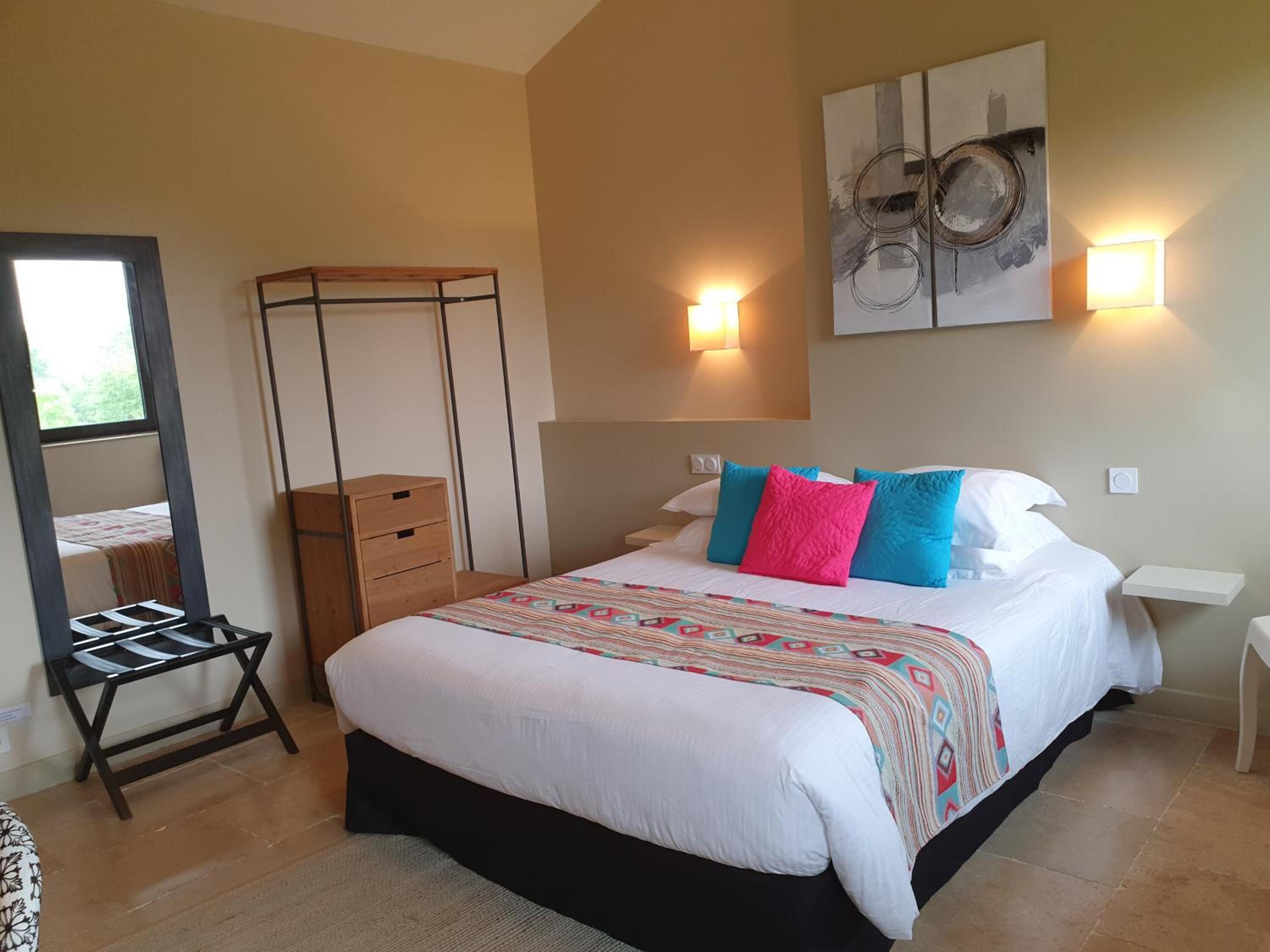Ein Schlafzimmer mit Bett, Nachttischen, einem Kleiderschrank, einem Spiegel und Bildern an der Wand.