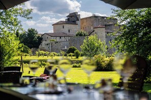 A historic stone building with a prominent tower, surrounded by lush greenery and a clear sky. - L'Auberge de Larressingle (Larressingle)