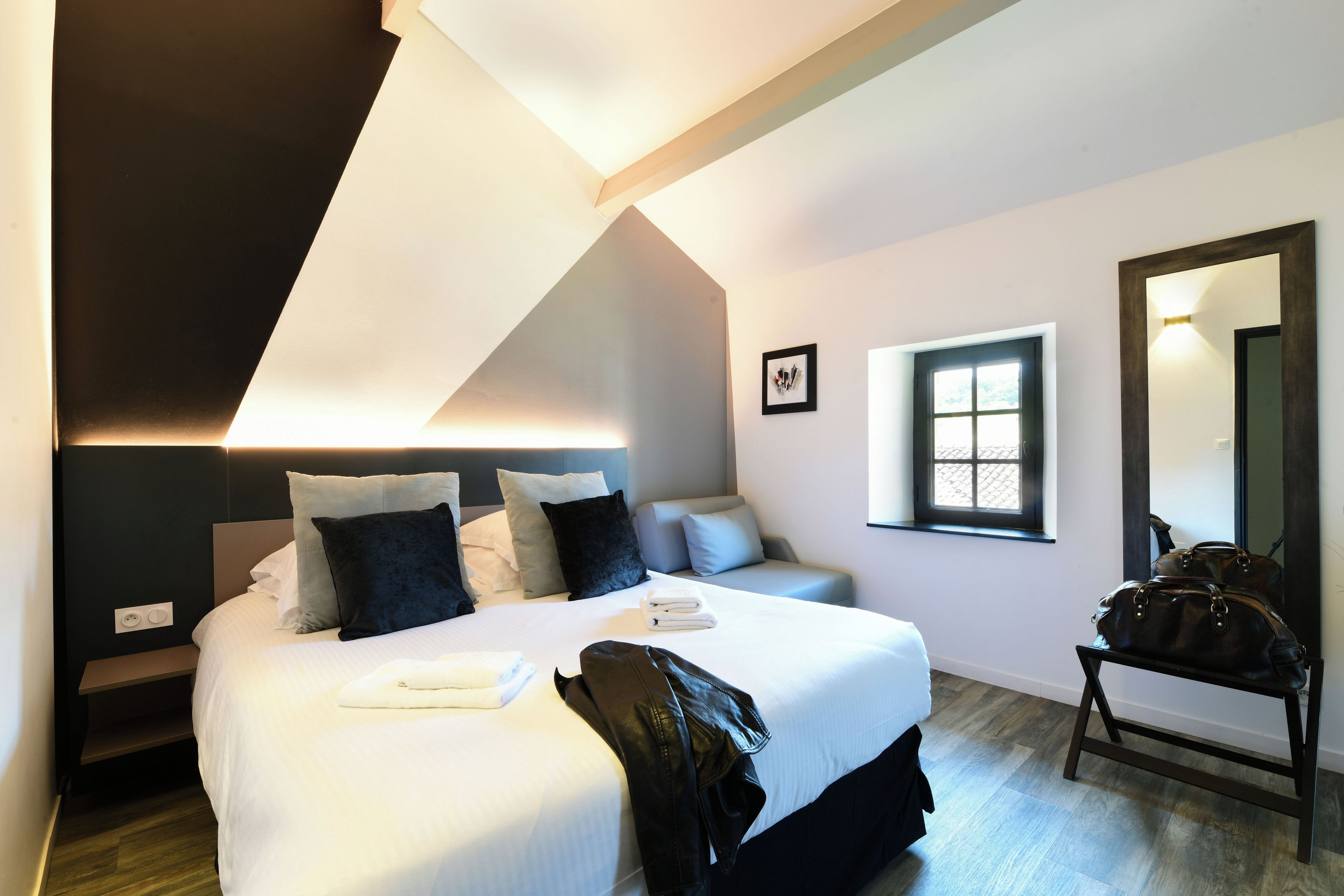 Una habitación de hotel moderna con una cama grande, un área de descanso, una ventana y un espejo.