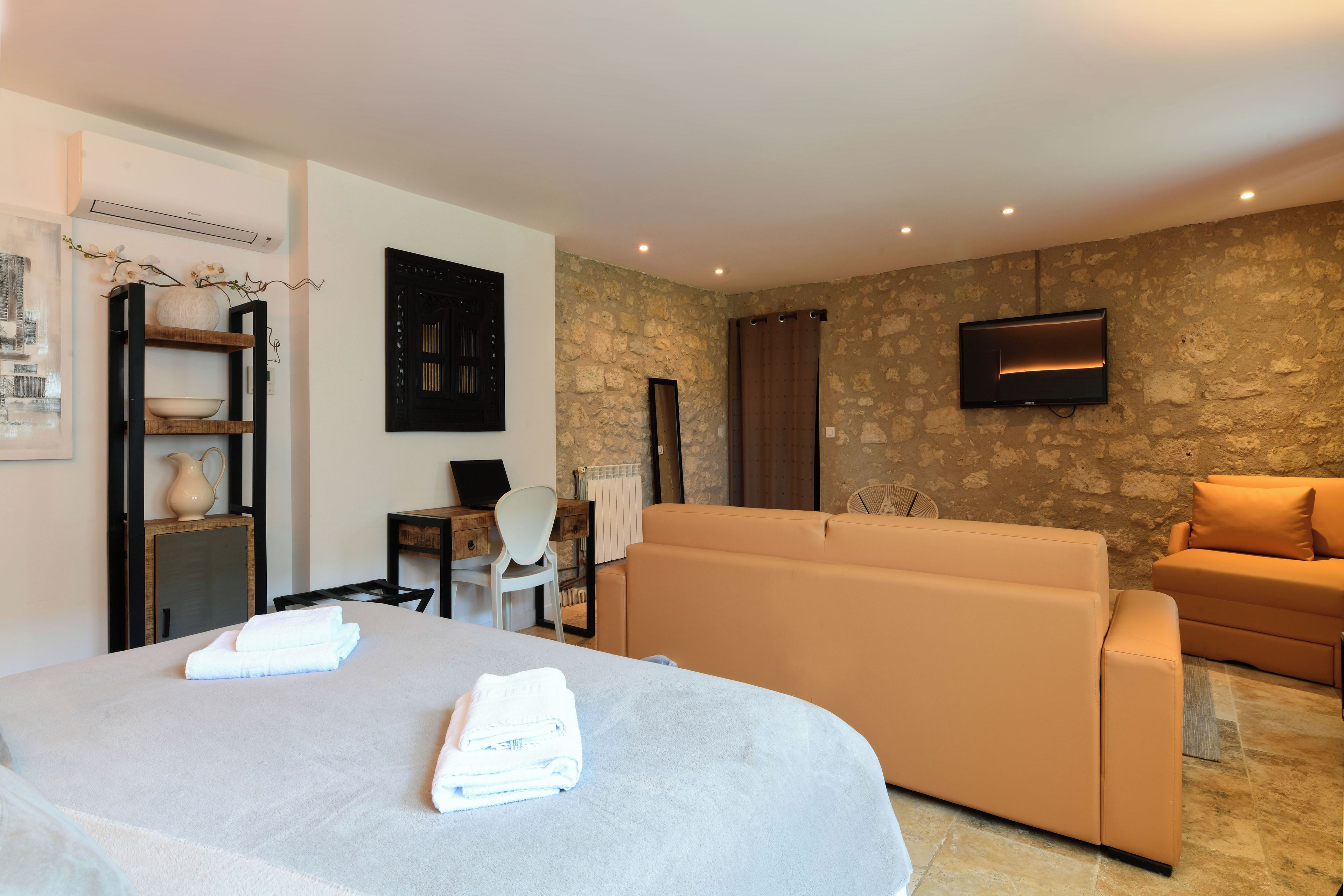 Ein Hotelzimmer mit Bett, einer Sitzecke, einem Fernseher und einer Steinwand.