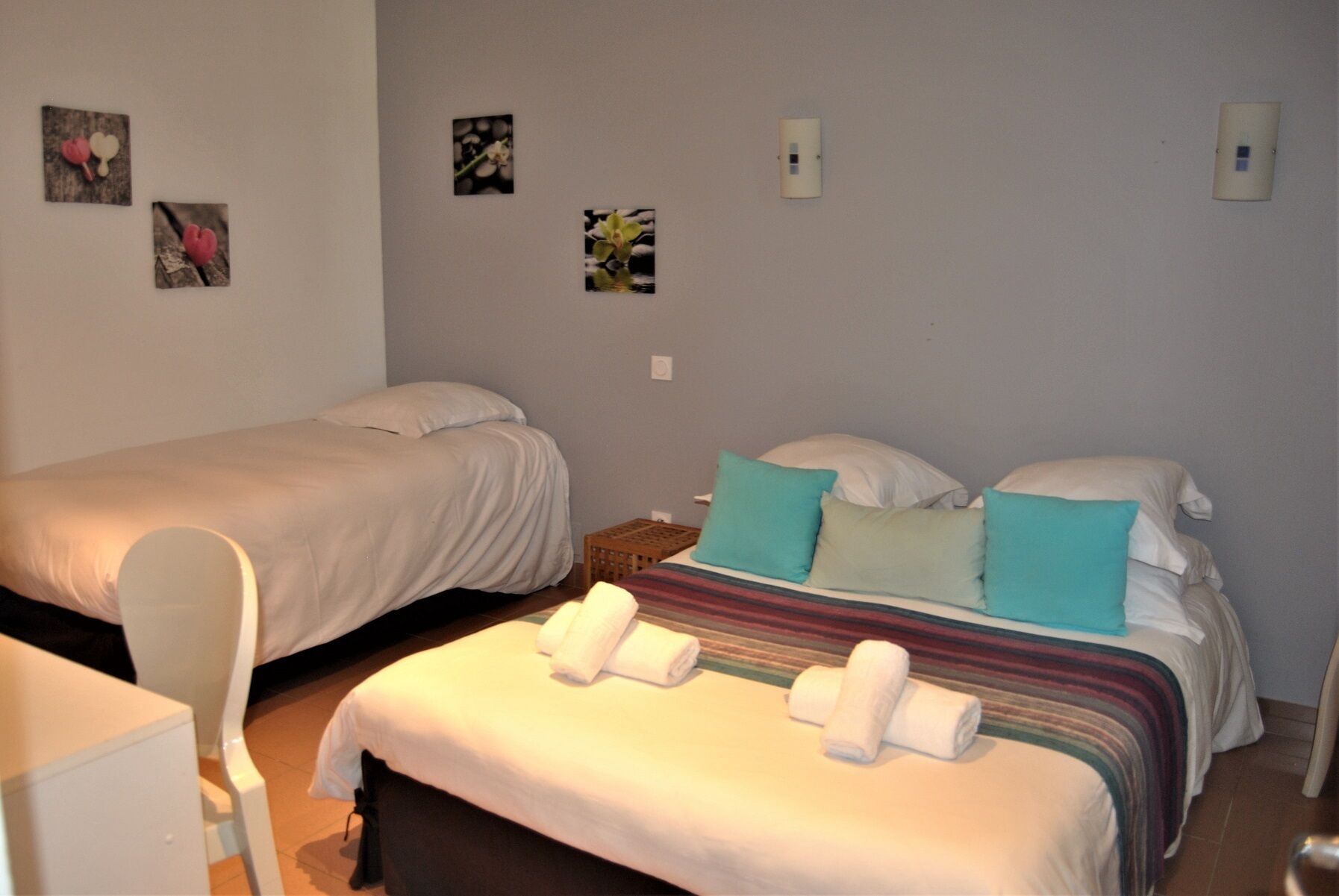 A hotel room with two beds, a small table, and a chair.