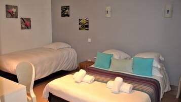 A hotel room with two beds, a small table, and a chair.