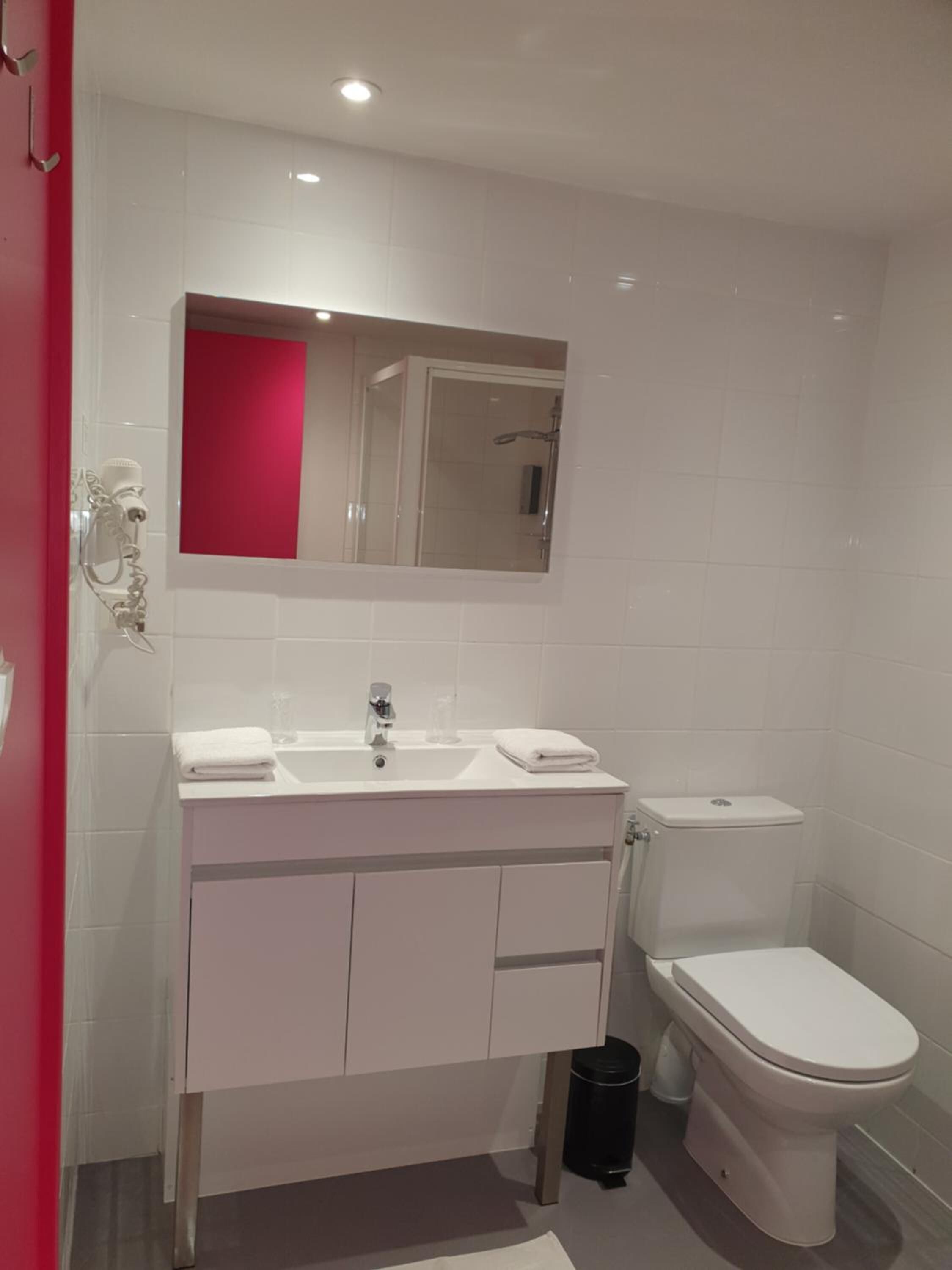 A modern bathroom with a white sink, mirror, and toilet.