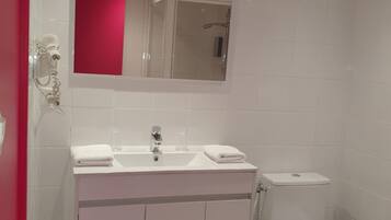 A modern bathroom with a white sink, mirror, and toilet.