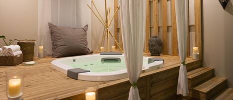 A wooden spa area with a hot tub, candles, and a decorative plant.