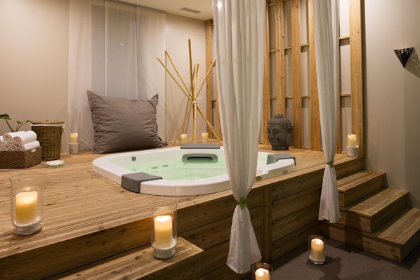 A wooden spa area with a hot tub, candles, and a decorative plant. - L'Auberge de Larressingle (Larressingle)