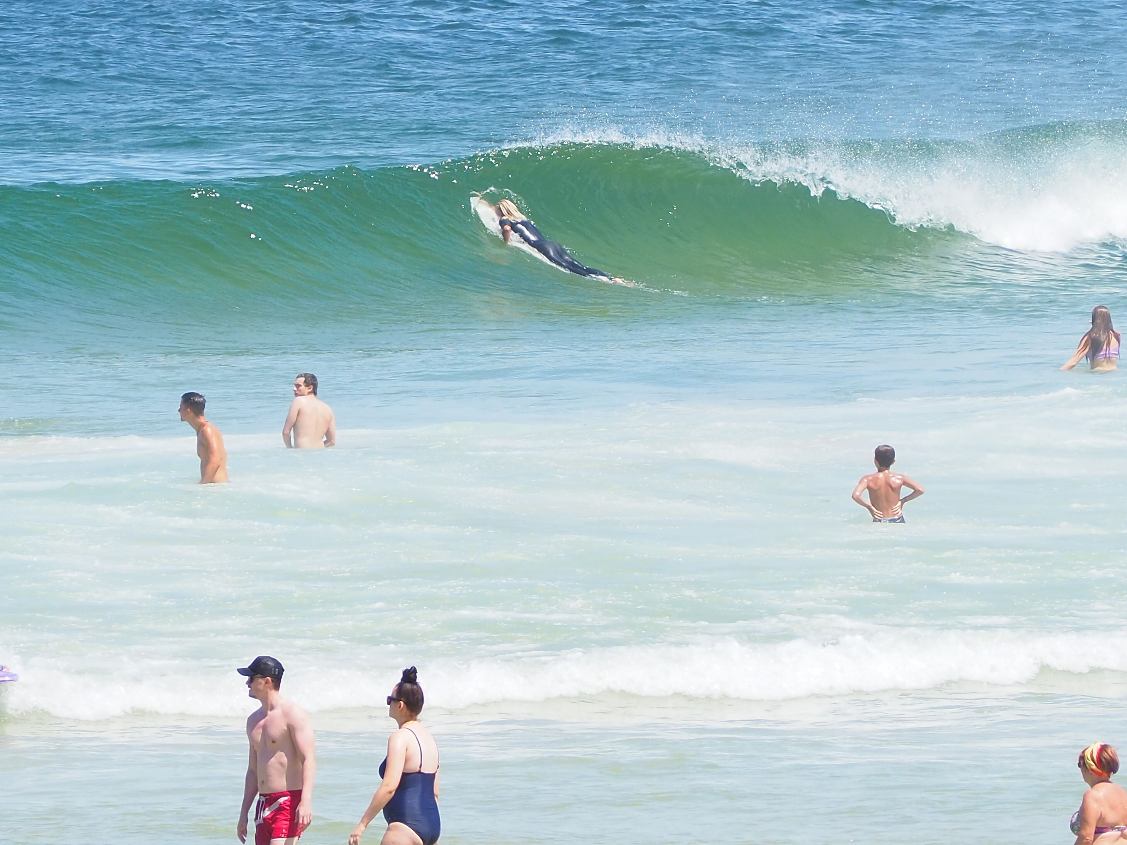 A beach scene with people swimming and surfing.