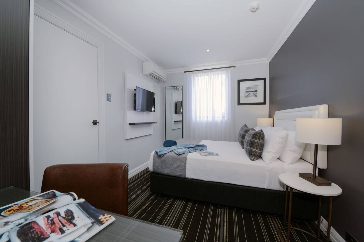 Una habitación de hotel con cama, televisión, escritorio y silla.