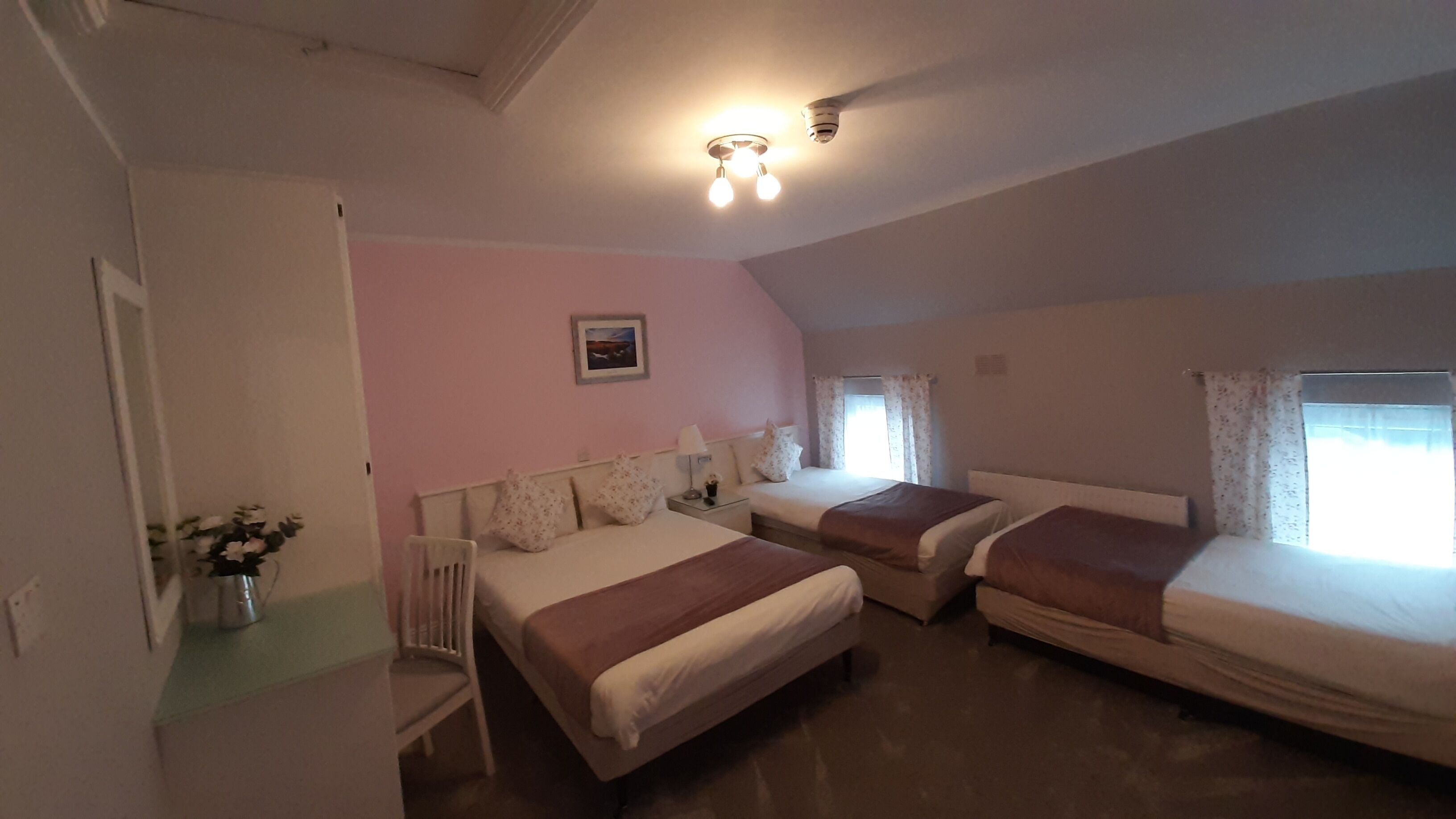 A bedroom with two beds, a nightstand, a lamp, and a picture on the wall.