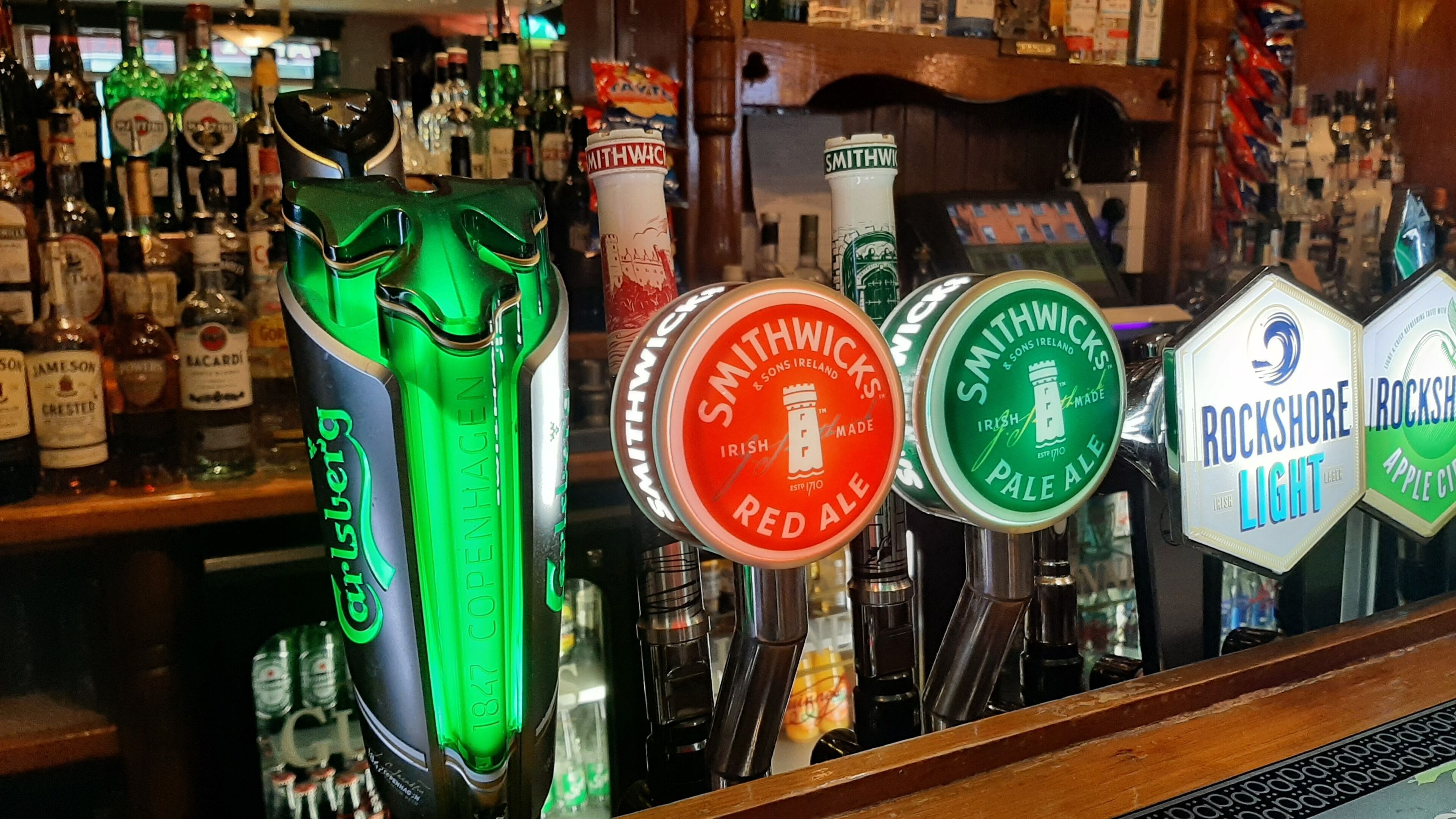 Un bar con diversas griferías de cerveza, incluyendo Smithwick's Red Ale y Rockshore Light.