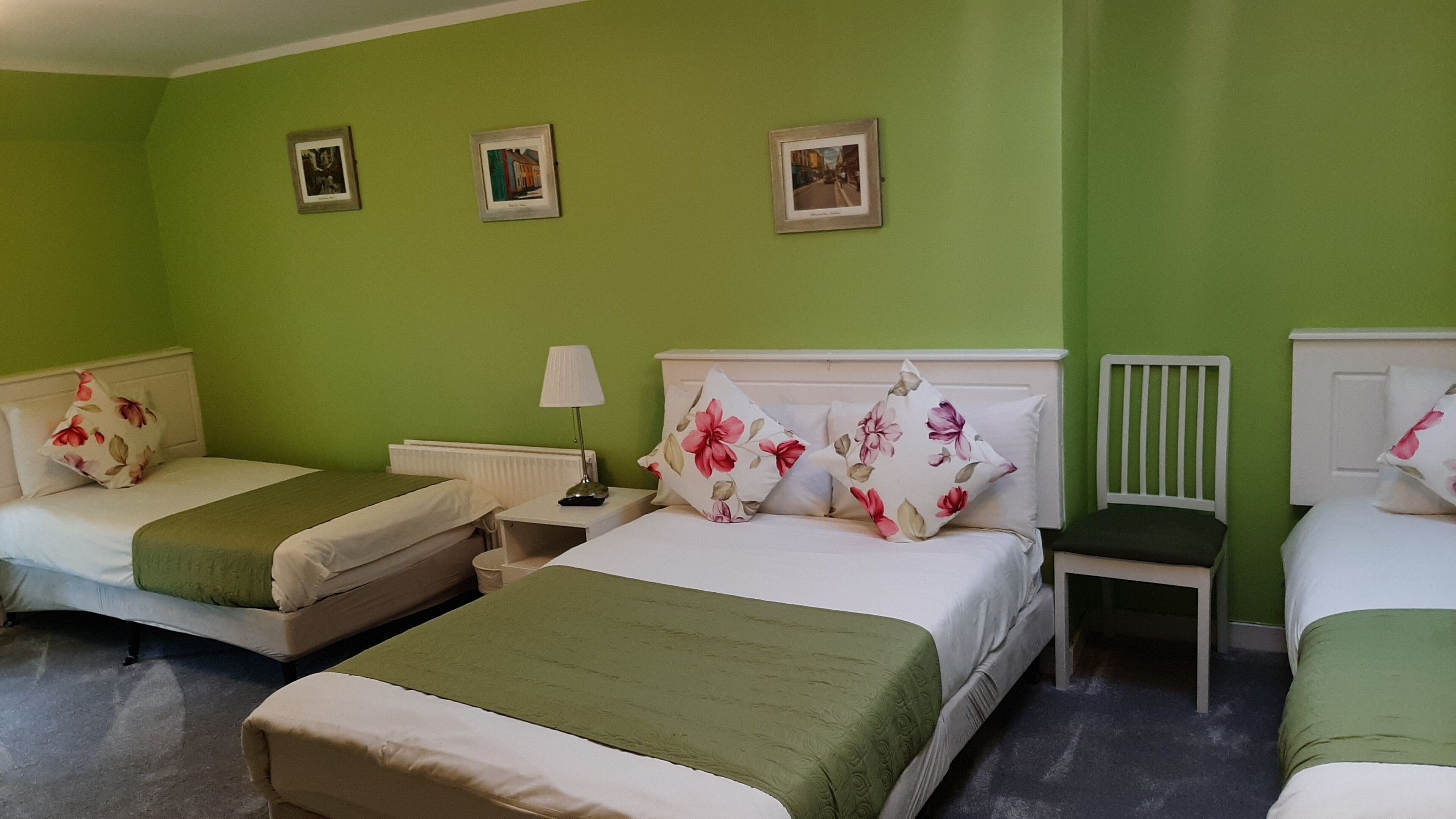 Une chambre d’hôtel avec deux lits simples, une table de chevet avec une lampe et une petite table.