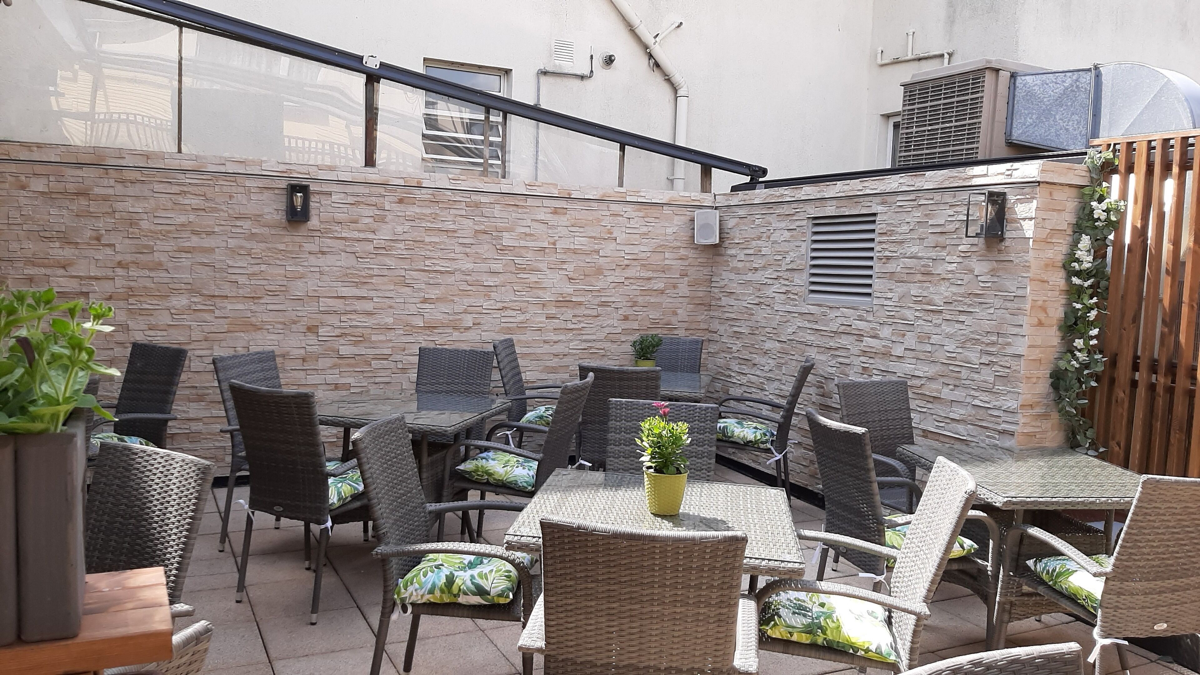An outdoor patio area with wicker furniture and potted plants.