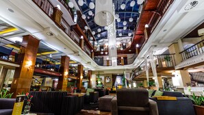 A spacious lobby with a high ceiling, multiple seating areas, and a central column.