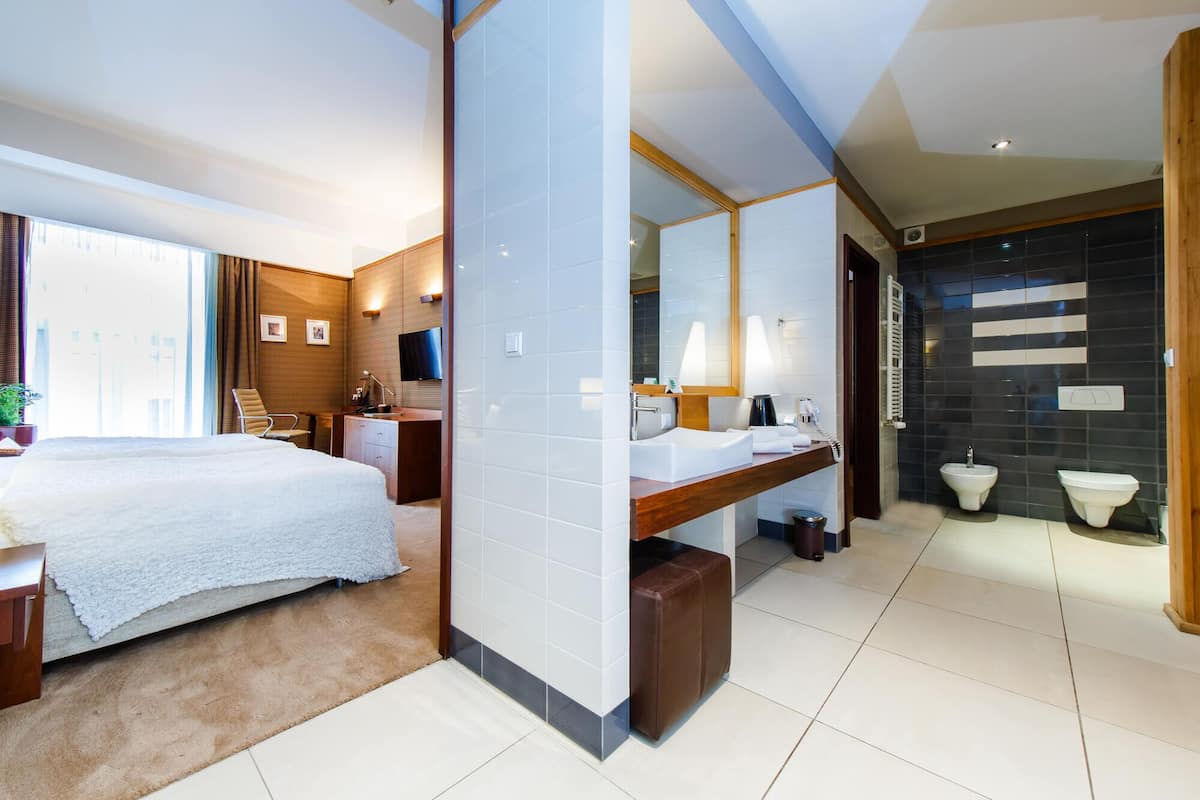 A modern hotel room with a bed, desk, and bathroom.