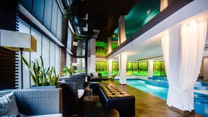 A modern indoor pool area with seating and a view of the pool.