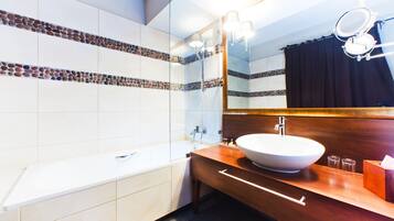 Un baño moderno con una bañera blanca, un mueble de tocador de madera con un lavabo grande y un espejo sobre el mueble.
