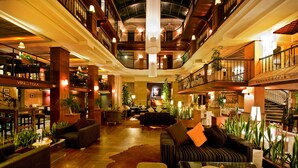 A spacious lobby with multiple seating areas, a staircase, and a restaurant sign.