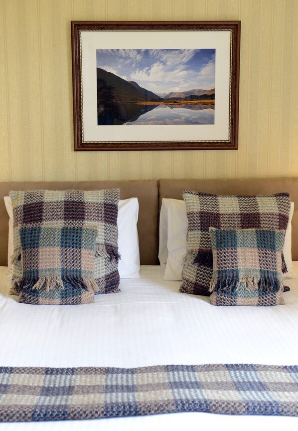 A bed with two pillows, a framed picture above, and a blanket on the bed.