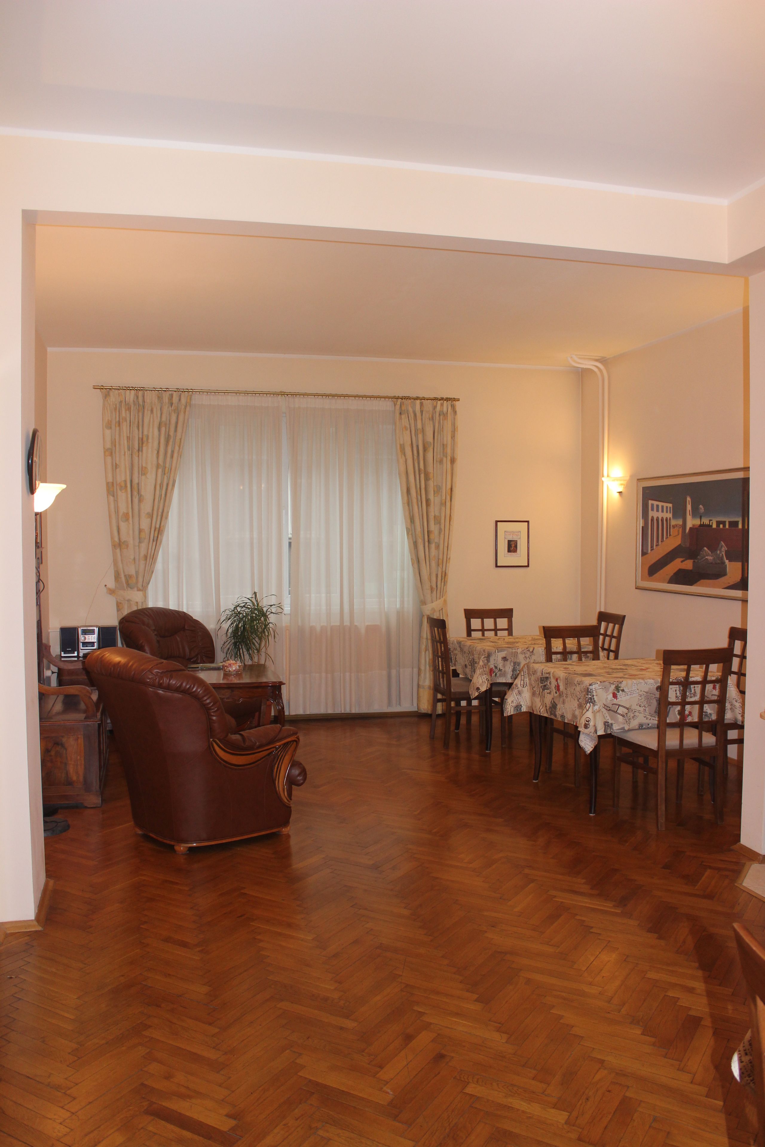 A dining area with a wooden table and chairs, a leather armchair, and a potted plant.