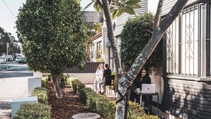 A building with a sign reading "AVOCA HANDWORKS" and a person sitting at a table with a laptop. - Avoca Randwick by Sydney Lodges (Randwick)