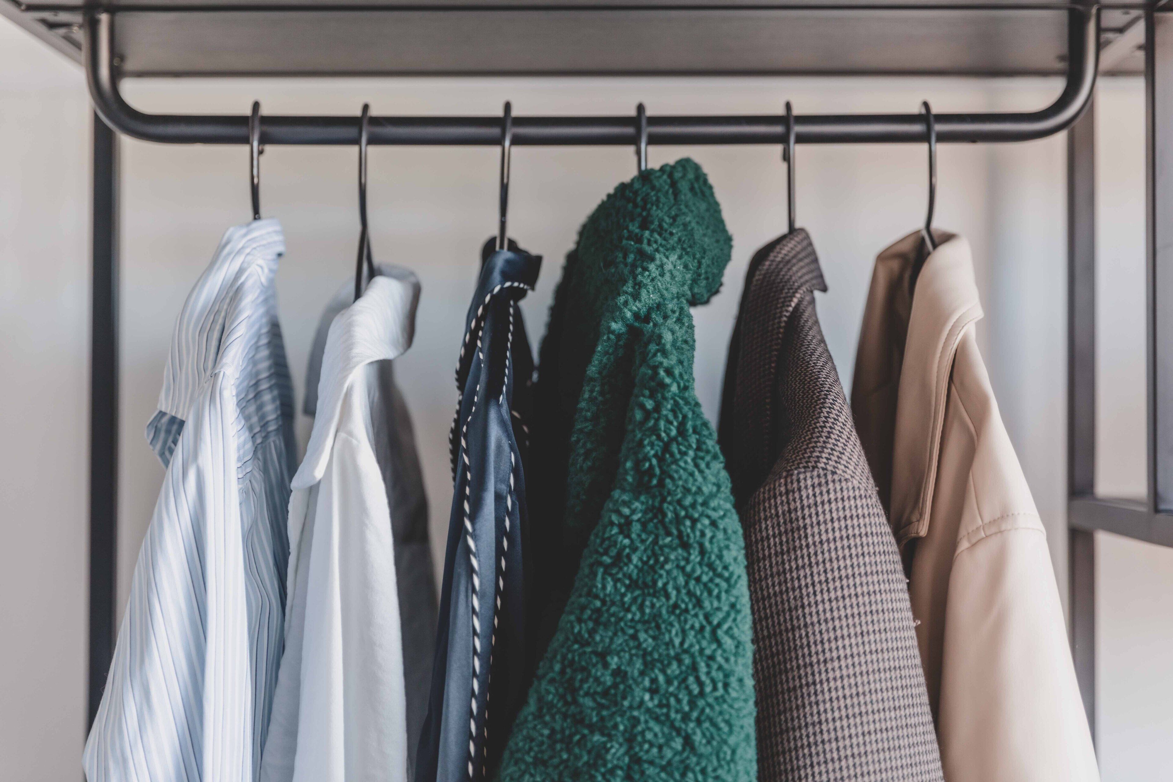 Un portabiti metallico con diversi capi di abbigliamento appesi.