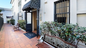 A narrow alleyway with a bench, a door, and a small garden area with plants. - Avoca Randwick by Sydney Lodges (Randwick)