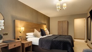 Una habitación de hotel moderna con una cama grande, mesitas de noche, un escritorio y un armario.