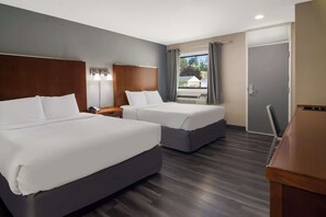 Habitación de hotel con dos camas, un escritorio y una ventana con cortinas.