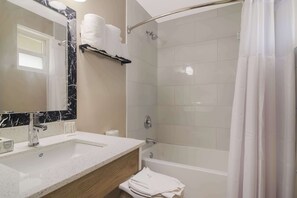 A modern bathroom with a marble sink, a glass-enclosed shower, and a white bathtub.