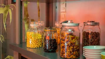 A shelf with glass jars containing various dried fruits and nuts, accompanied by stacked bowls.