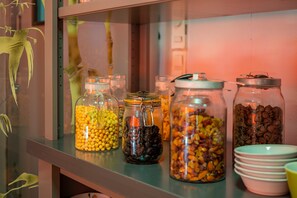 A shelf with glass jars containing various dried fruits and nuts, accompanied by stacked bowls. - Logis Hôtel Noemys Brive - Restaurant Le Teinchurier (Brive-la-Gaillarde)