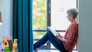 A person sitting by a window, reading a book. - Logis Hôtel Noemys Brive - Restaurant Le Teinchurier (Brive-la-Gaillarde)