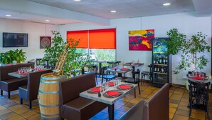 A restaurant with booths and tables, some with red napkins, and a large wooden barrel. - Logis Hôtel Noemys Brive - Restaurant Le Teinchurier (Brive-la-Gaillarde)