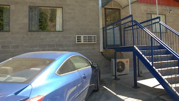 A blue car parked in front of a building with a sign reading "HOTEL DEORO".