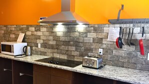 Una cocina con microondas, tostadora y estufa a gas sobre una encimera de granito.