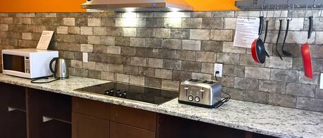 A kitchen with a microwave, toaster, and gas stove on a granite countertop.