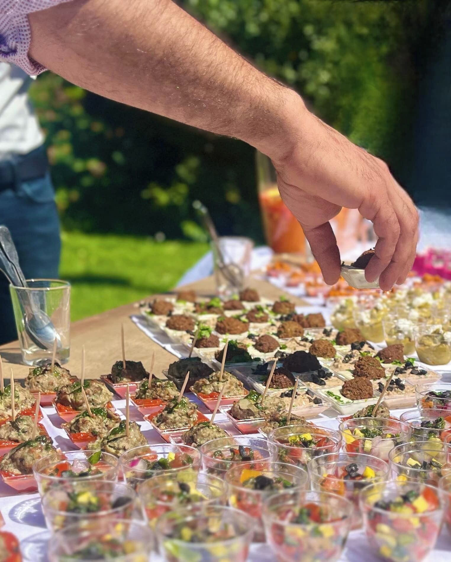Una persona sirve comida desde una bandeja en un evento al aire libre.