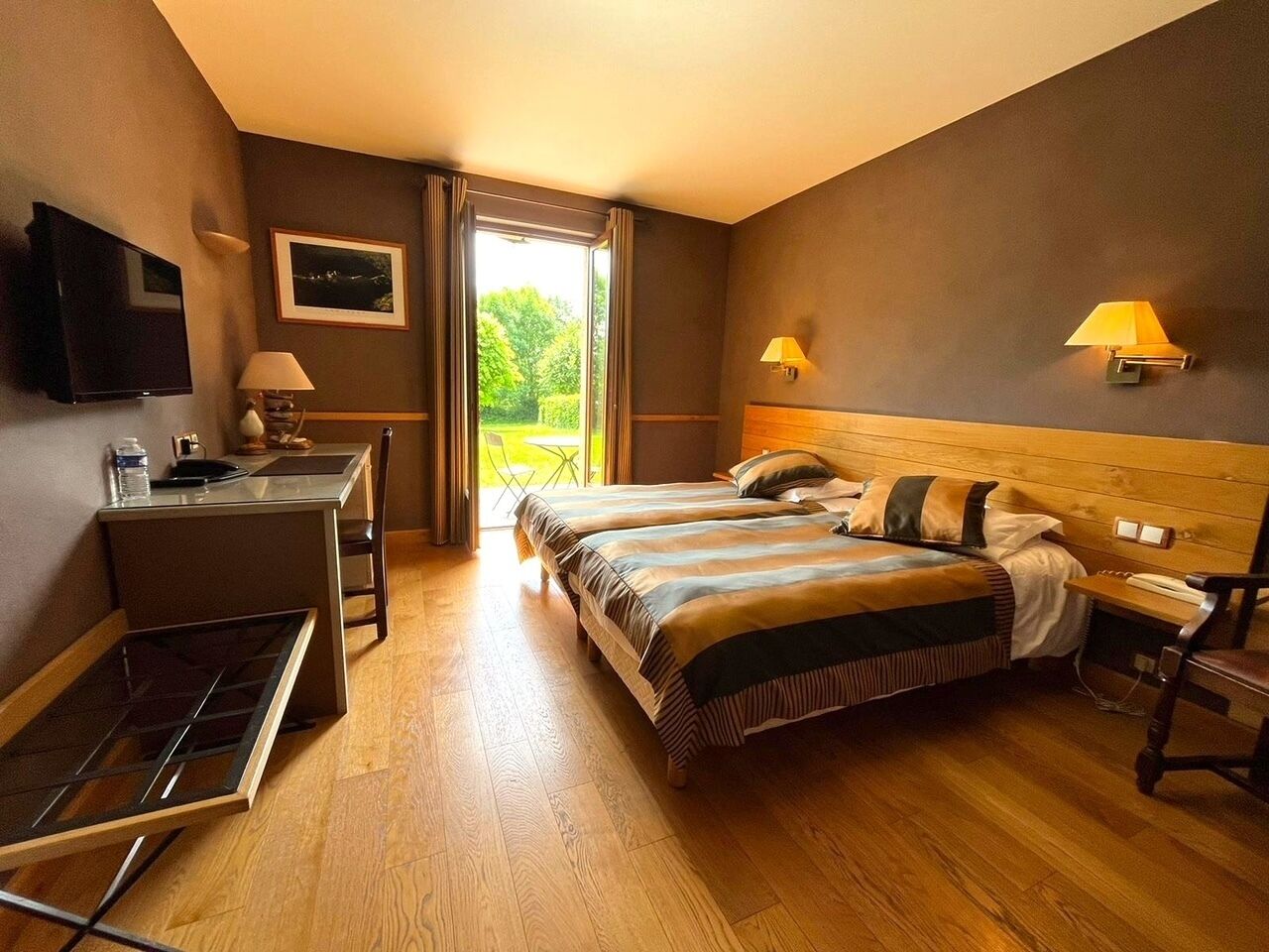 Een hotelkamer met een bed, bureau, stoel, een televisie en een raam met gordijnen.