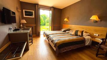 Een hotelkamer met een bed, bureau, stoel, een televisie en een raam met gordijnen.