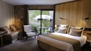 Una habitación de hotel con una cama grande, un sofá, una silla y una mesa con paraguas.