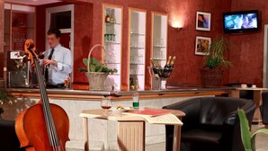 A lobby with a reception desk, a candelabra, a television, and a large plant. - Le Luth (Mirecourt)